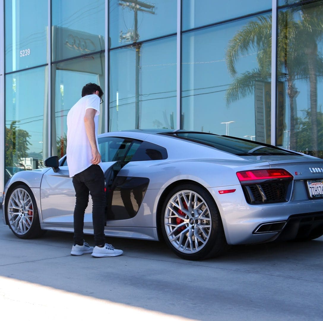 A man standing next to a silver car.