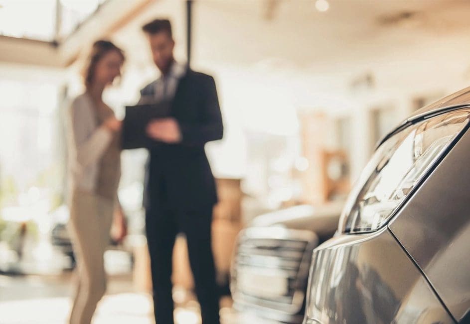 A man and woman standing in front of a car.